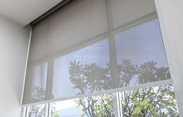 Roll Blinds on the windows, the sun does not penetrate the house. Window in the Interior Roller Blinds. Beautiful Blinds on the Window, the Sun and Heat Protection, the Perfect Windows Interior Decor